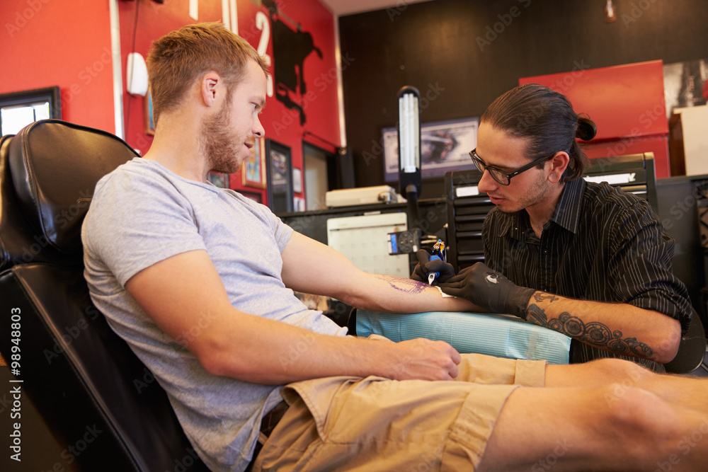Artist at work on a sleeve tattoo